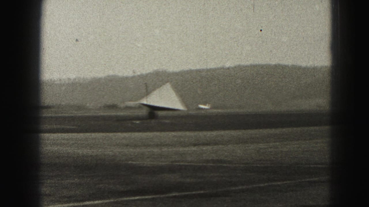 1975 Harrisburg-area airport view with a triangular wind indicator near the runway and hills along the horizon.