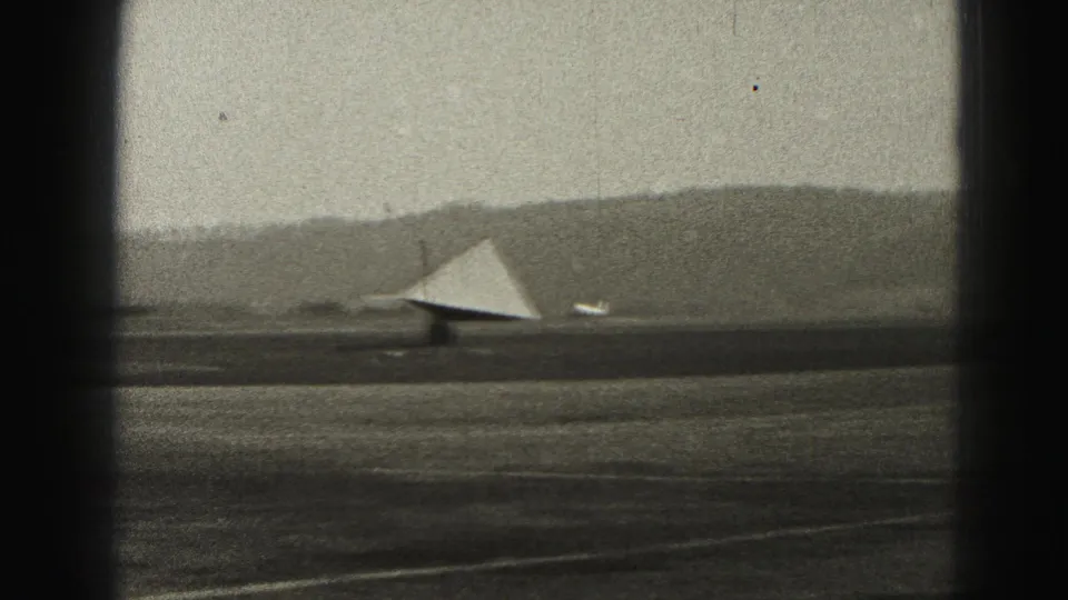 1975 Harrisburg-area airport view with a triangular wind indicator near the runway and hills along the horizon.