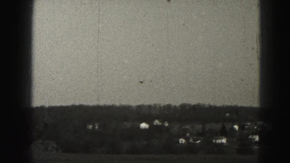 1975 Harrisburg-area 8mm frame with distant houses, a treeline, open land, and heavy dark window framing.