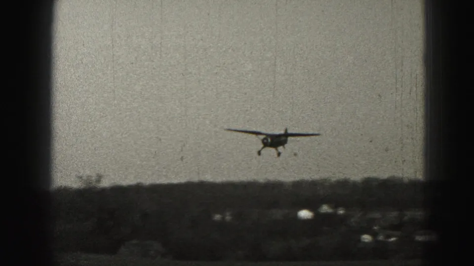 A small propeller airplane appears in the distance over a low Harrisburg-area landscape in 1975 8mm home-movie footage.