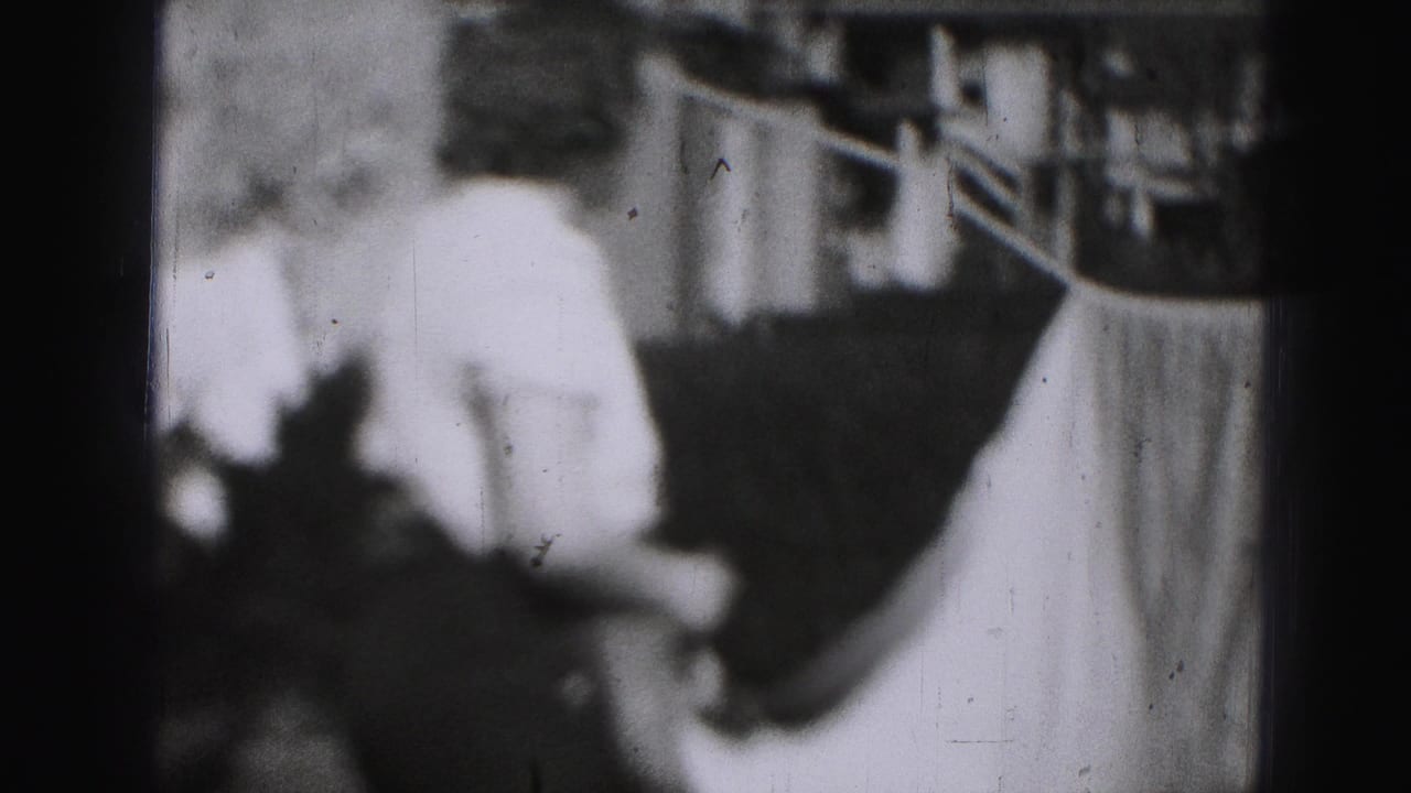 The woman turns away from the camera near a bright sheet on a backyard clothesline in 1975 Harrisburg footage.