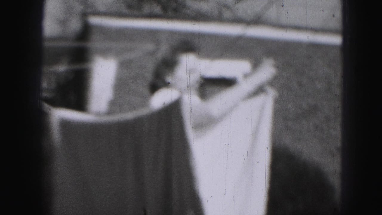 1975 Harrisburg 8mm frame showing pale laundry on a clothesline beside an outdoor yard structure.