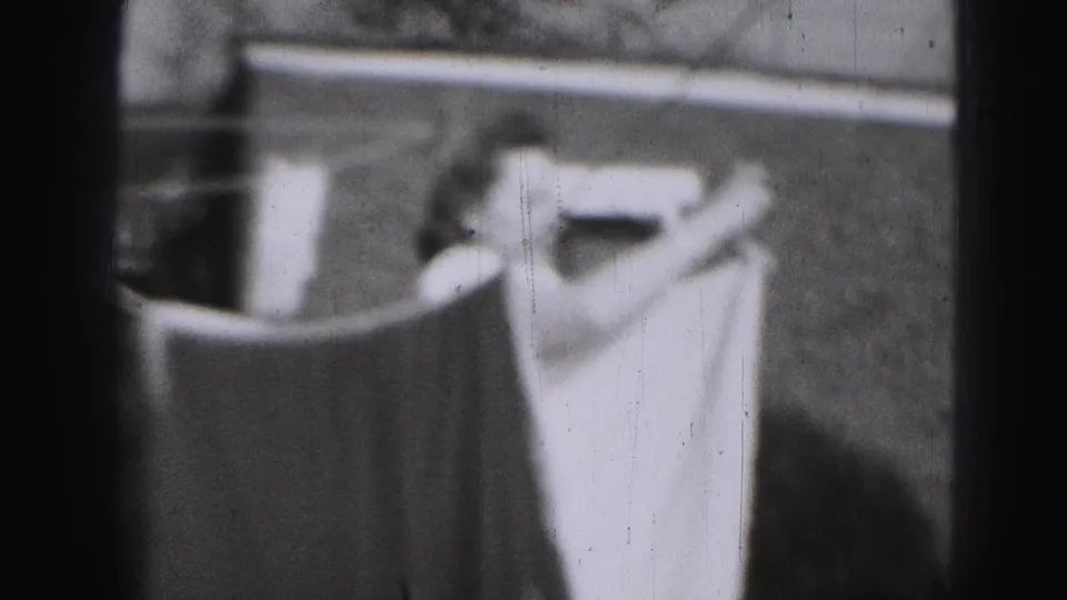1975 Harrisburg 8mm frame showing pale laundry on a clothesline beside an outdoor yard structure.