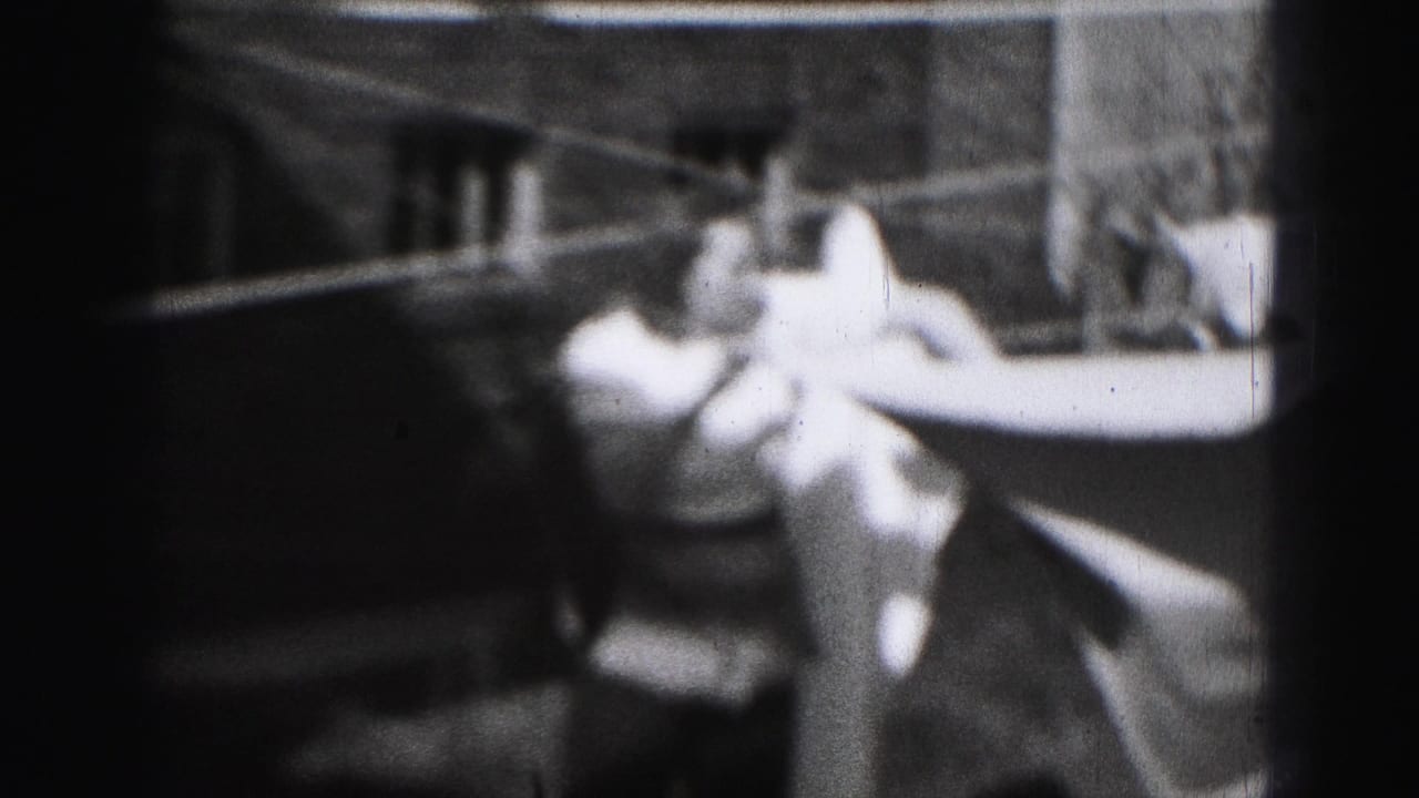 Woman reaches toward light laundry on an outdoor clothesline.
