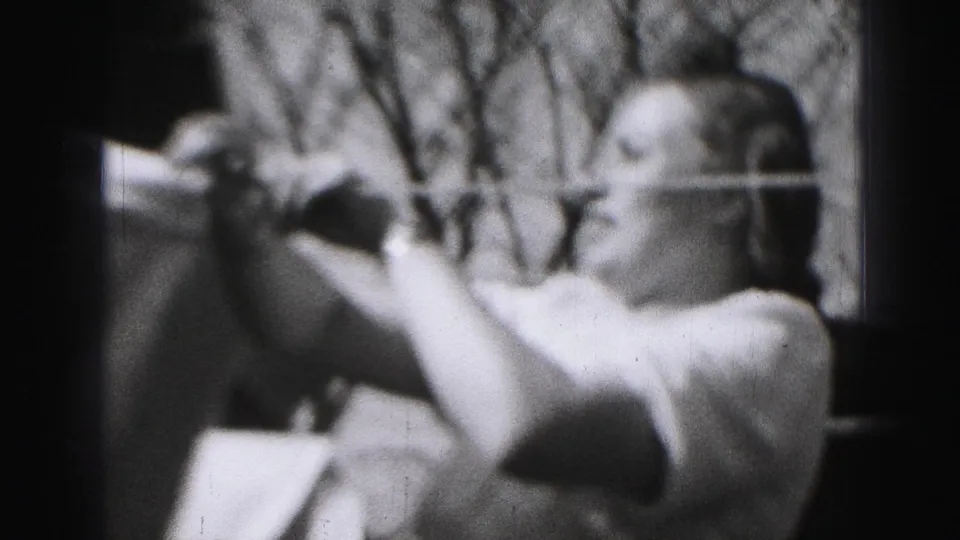 A close final frame shows the woman adjusting pins and fabric on the clothesline, with tree branches behind her.