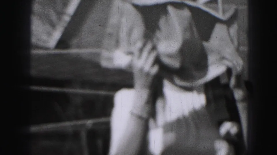 The woman appears closer to the camera in the Harrisburg backyard, with the hanging sheet and fence behind her.