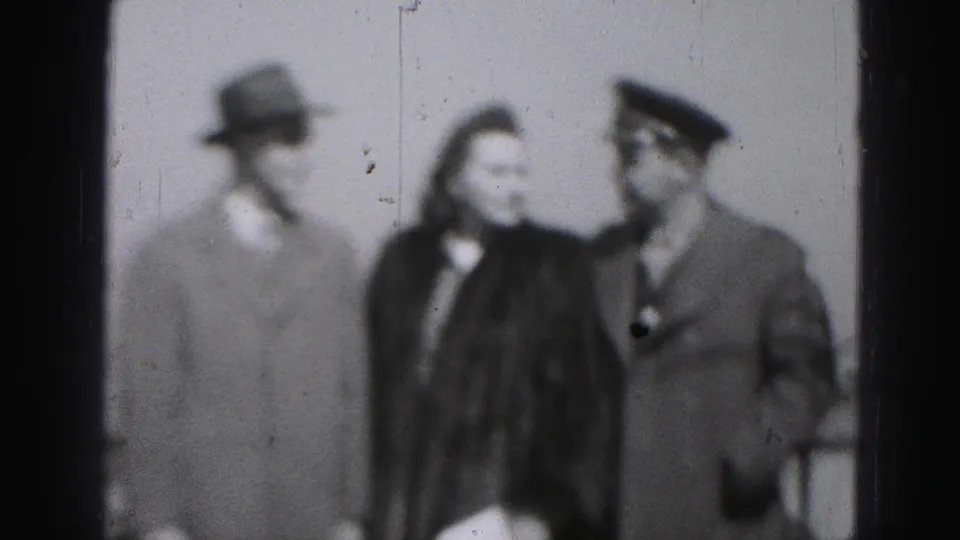 In this Harrisburg home-movie frame, the woman appears to turn toward the uniformed man as the group continues their brief exchange.