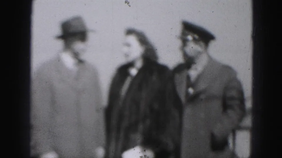 The 1975 Harrisburg frame shows a close grouping of adults in formal outerwear, with the woman turned toward the uniform-like cap.