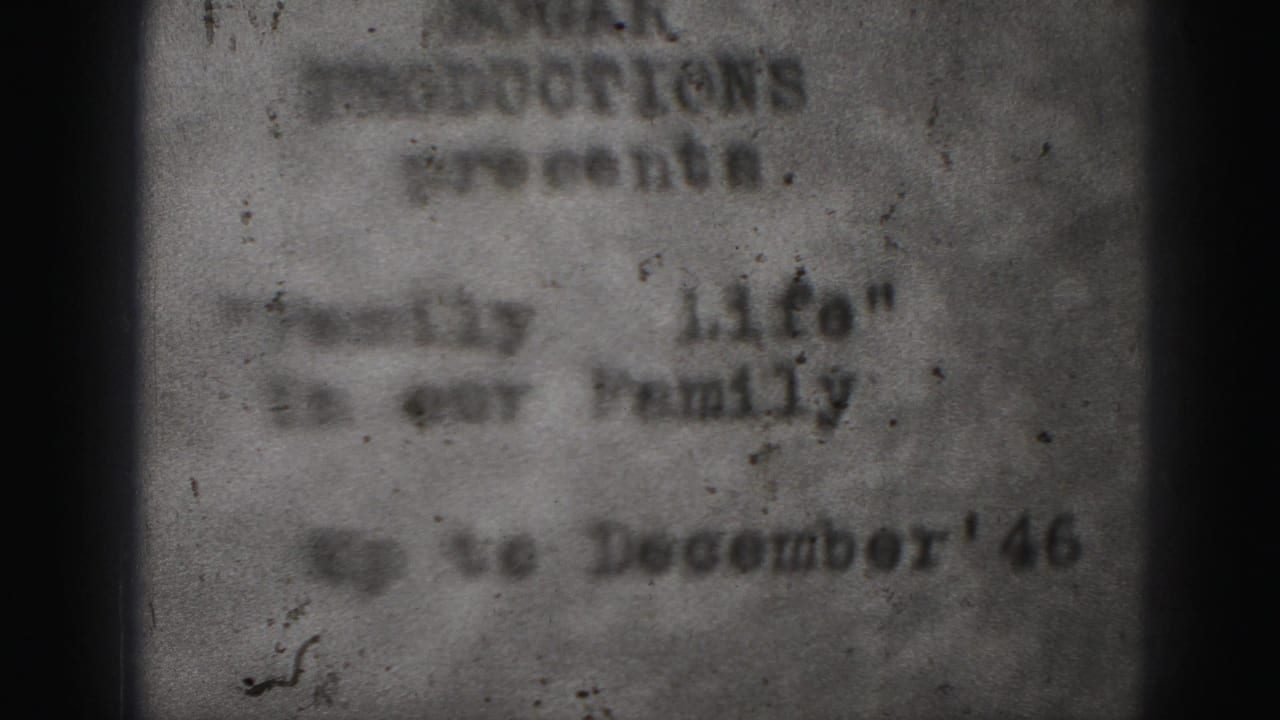 Blurred typed home-movie title card with dark film edges and visible grain.