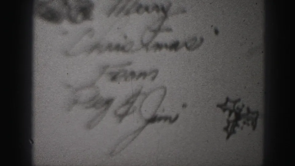 Handwritten Christmas greeting reading as a message from Peg and Jim, with a small star drawing, in a 1946 family-film clip.