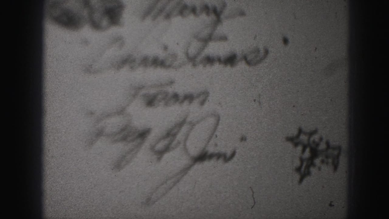 Blurred handwritten Christmas note with signatures and a small decorative mark.