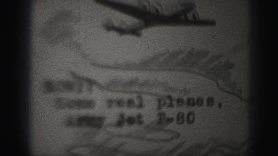 Soft 1975 Harrisburg home-movie frame showing a hand-drawn jet labeled with partly legible Army Jet F-80 wording.