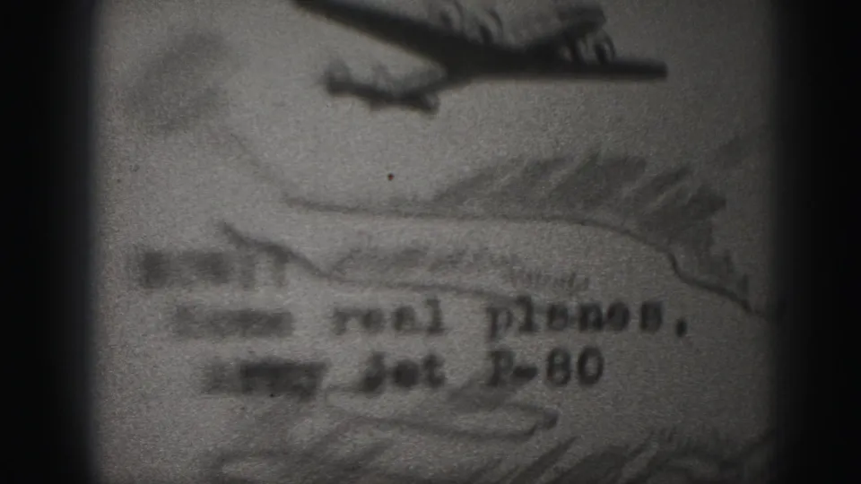 1975 8mm frame from Harrisburg showing a soft, grainy filmed photograph of an airplane with partially readable text referencing an Army Jet P-80.