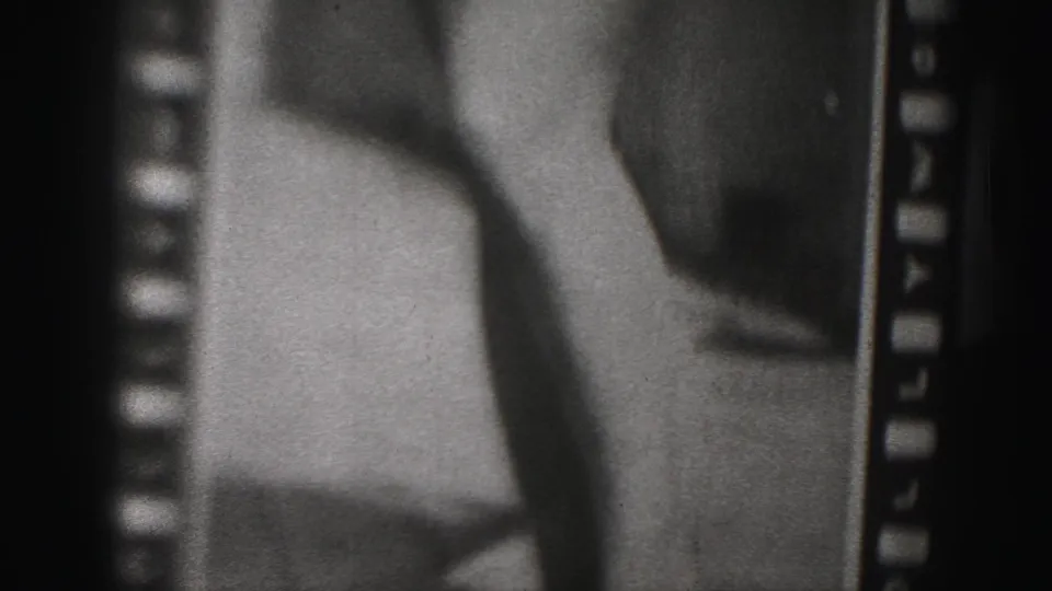 1975 Harrisburg-area 8mm frame showing a close cropped view of a woman in swimwear, with legs, lower torso, grain, and sprocket-edge framing visible.