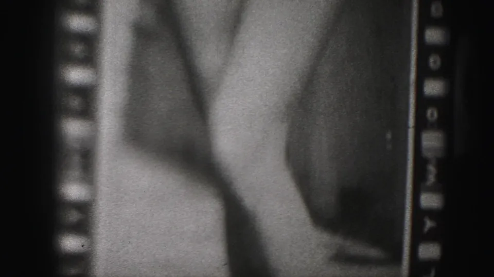 1975 Harrisburg-area home-movie frame with a close view of a woman's torso and arm in swimwear, bordered by visible 8mm sprocket holes.