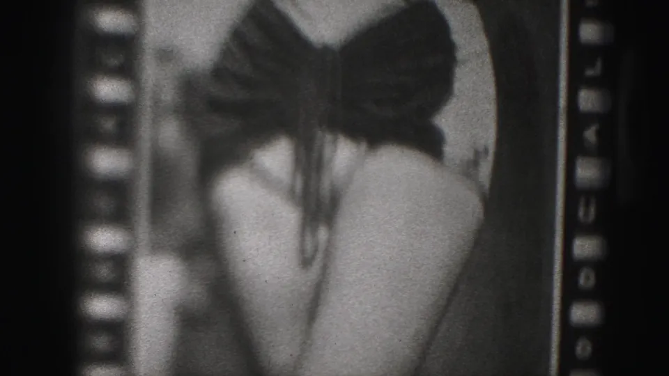 1975 Harrisburg-area 8mm frame showing a woman's bikini top with a central bow detail, cropped closely across the torso.