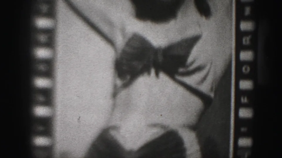 1975 Harrisburg-area home-movie frame showing a close crop of a woman's bikini bow and torso, with sprocket holes and grain visible.