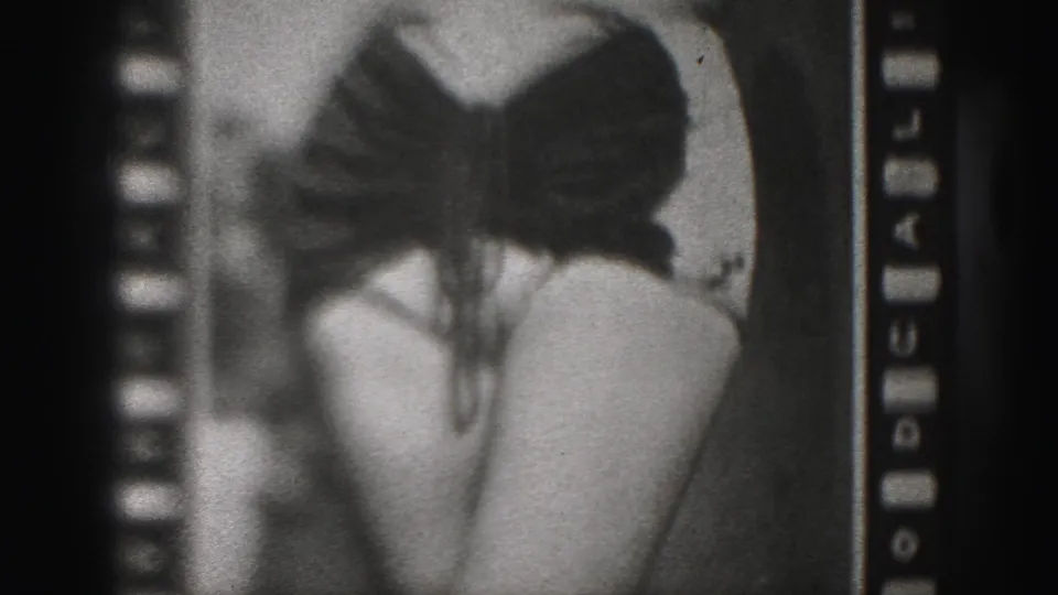 1975 Harrisburg home-movie frame showing a woman in a dark bikini from behind, with soft grain and cropped contact-sheet framing.