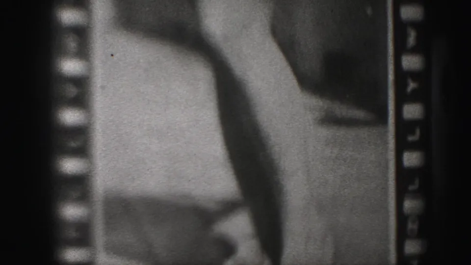 1975 Harrisburg 8mm frame showing a poster or display with bare legs, feet, and partially visible printed name text.