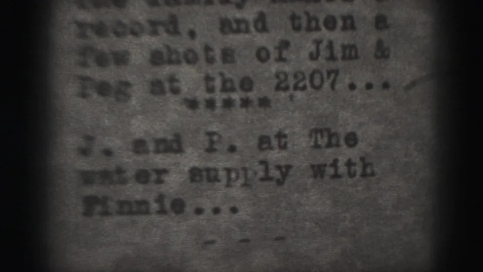 1975 Harrisburg home-movie frame showing a soft, grainy close-up of typed family notes on paper.