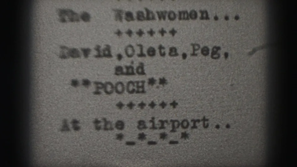 1975 Harrisburg 8mm frame showing a typewritten family-film card with names, Pooch, and an airport scene note.