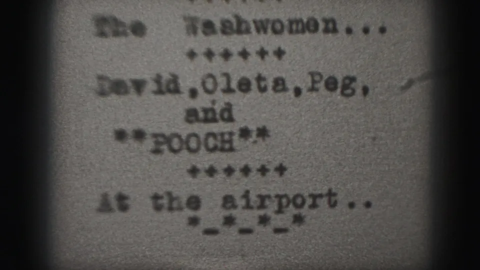 1975 Harrisburg home-movie frame showing a soft, grainy typed title card for The Washwomen with cast names and airport wording.