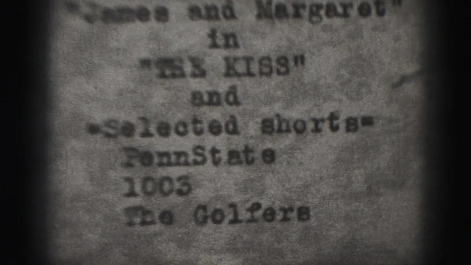 1975 Harrisburg 8mm frame showing a blurred typewritten credit card with partial names, short-film references, grain, and dark borders.