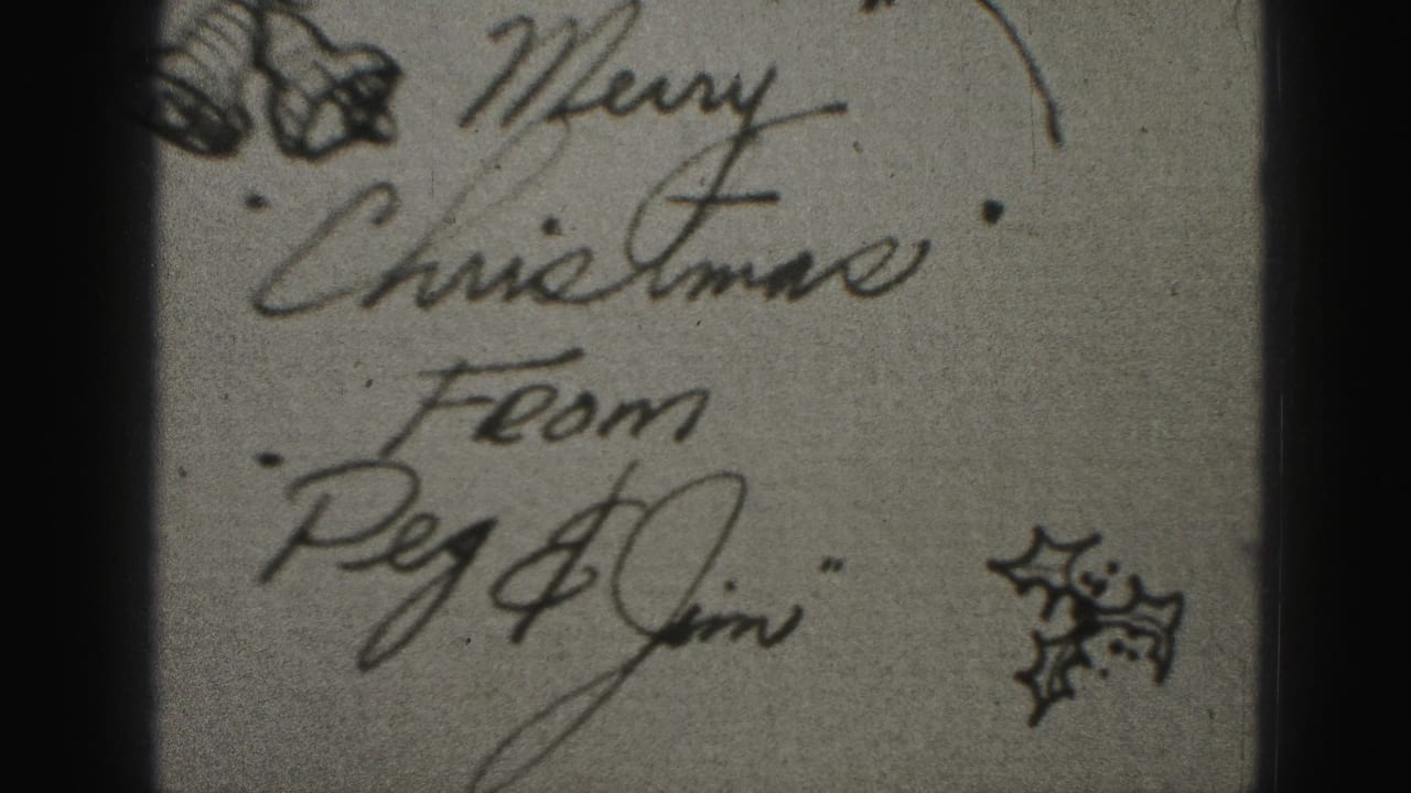 Handwritten Christmas card detail with cursive greeting and small holly drawings.