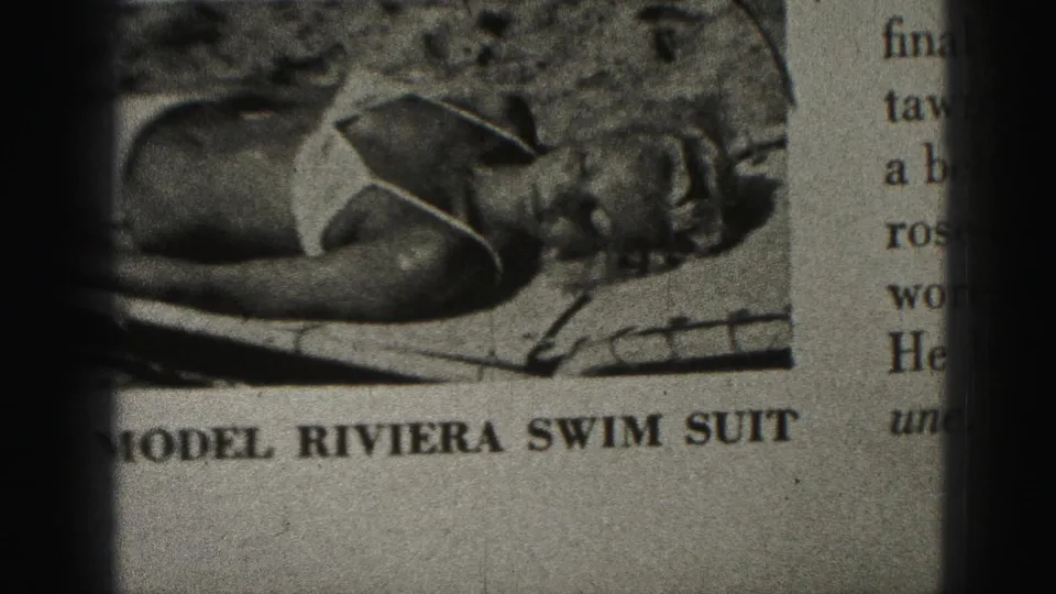 1975 Harrisburg 8mm frame showing a printed swimsuit advertisement or article page with a reclining model and readable Riviera swim suit caption.