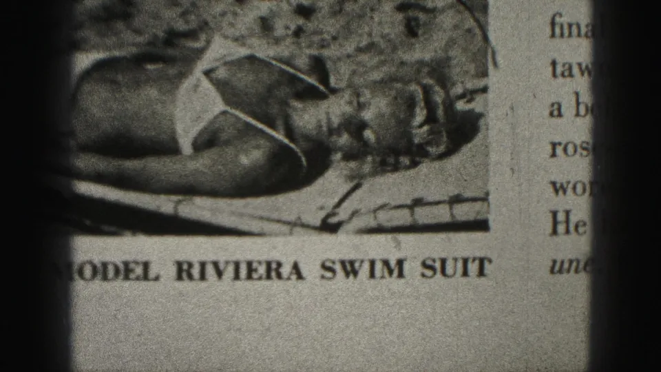 1975 Harrisburg 8mm frame showing the lower part of the Riviera swimsuit ad, adjacent printed article text, dark gate edges, and grainy monochrome texture.