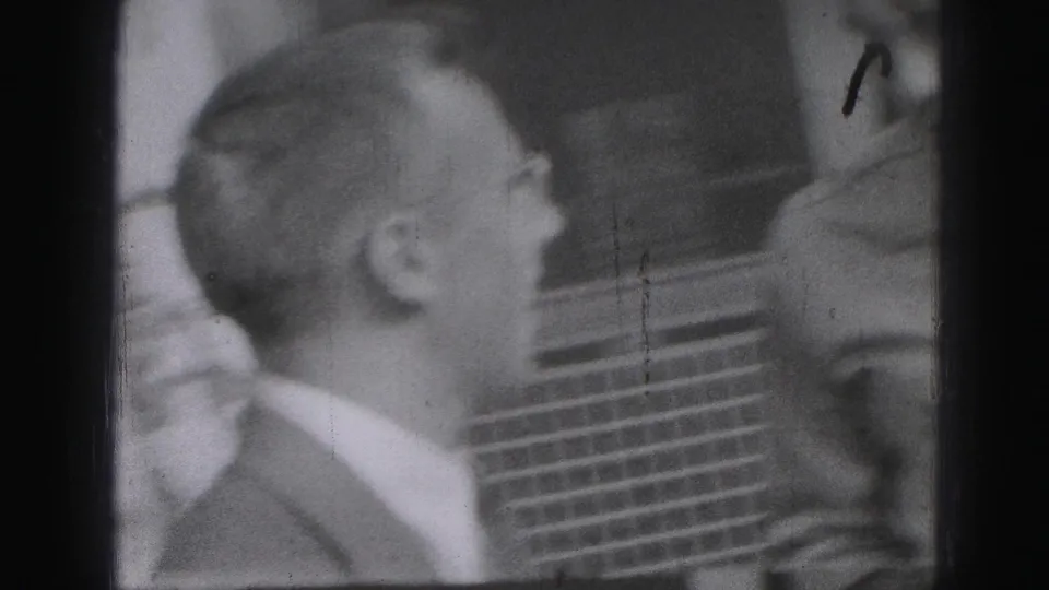The suited man faces another partially visible adult man during a brief outdoor conversation in Harrisburg, Pennsylvania.