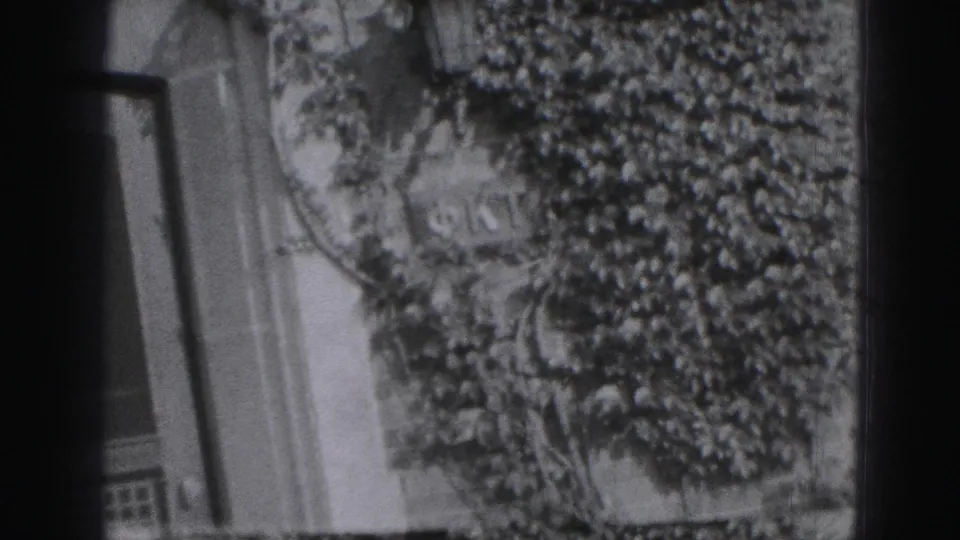 A tilted 8mm frame shows an ivy-covered residential wall and trees, likely near the lawn seen earlier in the Harrisburg clip.
