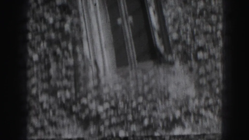 Soft 8mm frame from Harrisburg showing ivy spread across an older exterior wall with narrow windows nearby.
