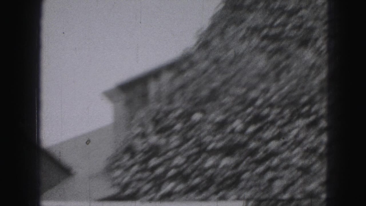 Black-and-white 8mm view of a house exterior in Harrisburg metadata context, with a sloped roofline and textured wall.