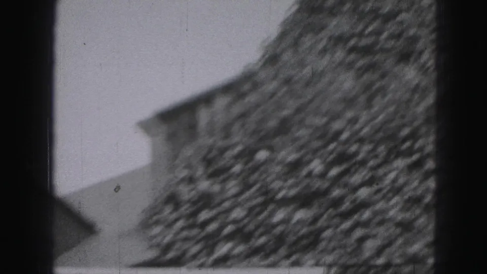 Black-and-white 8mm view of a house exterior in Harrisburg metadata context, with a sloped roofline and textured wall.