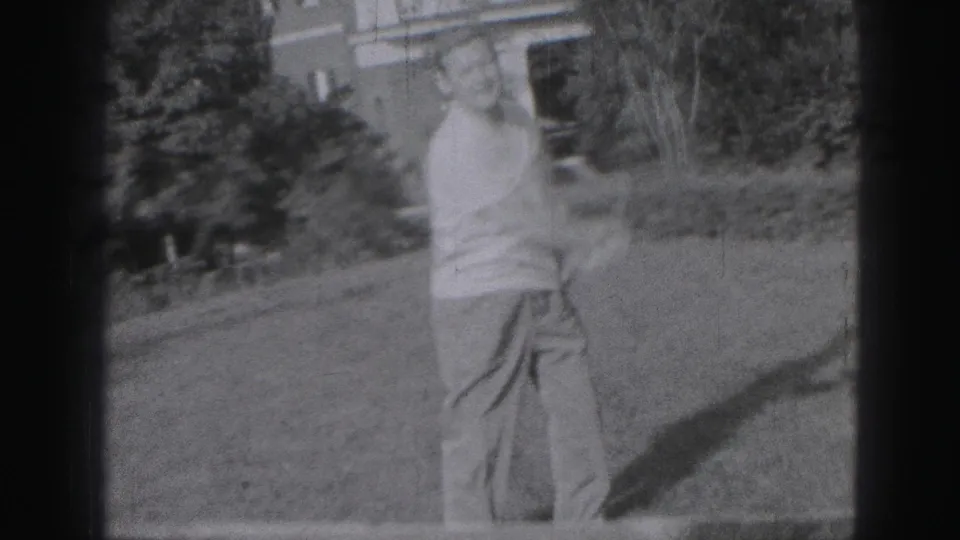 The man follows through with a golf swing on a residential lawn in Harrisburg, Pennsylvania, captured with soft 8mm motion blur.