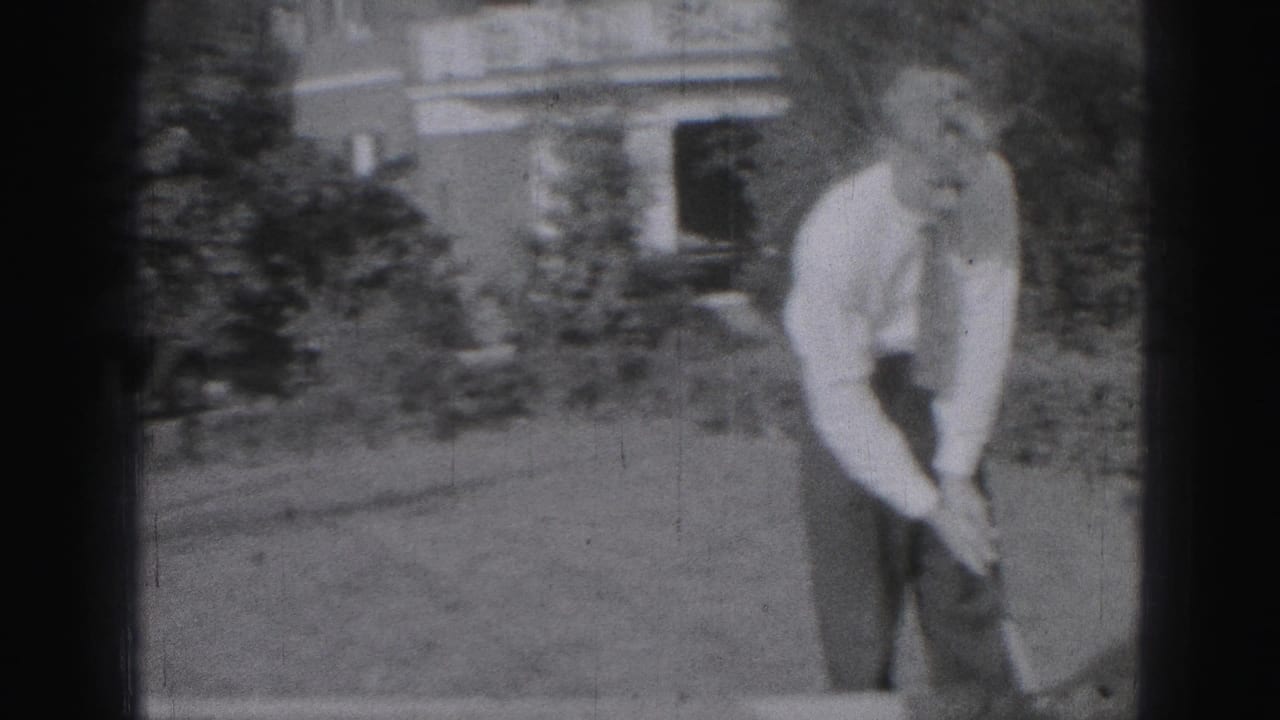 Man in white shirt and tie bends over a golf club on a backyard lawn.