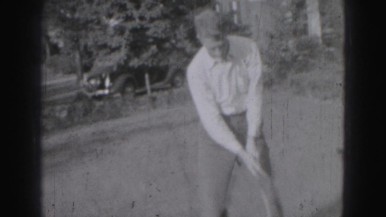 A young man in Harrisburg, Pennsylvania, bends into a golf stance with a club in black-and-white 8mm footage from 1975.