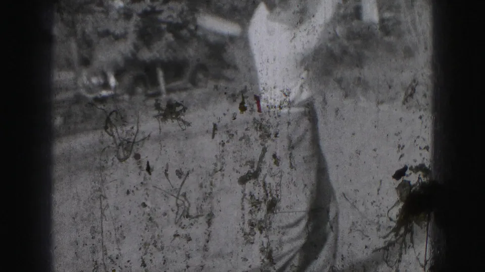 The 1975 8mm frame shows a partial view of the golfer's lower body and club area, with strong scratches and dust visible.