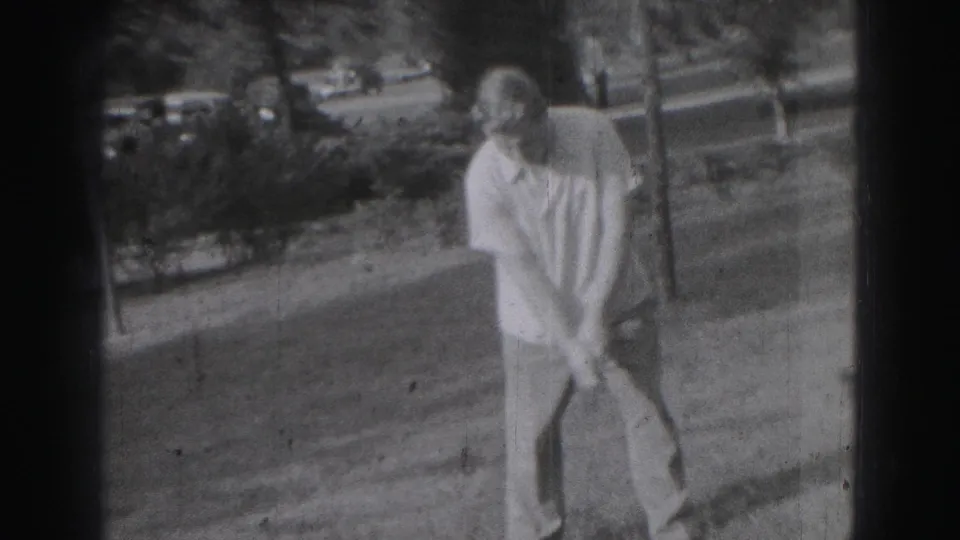 Adult man in Harrisburg, Pennsylvania, stands on a grassy yard with a golf club in 1975 home-movie footage.