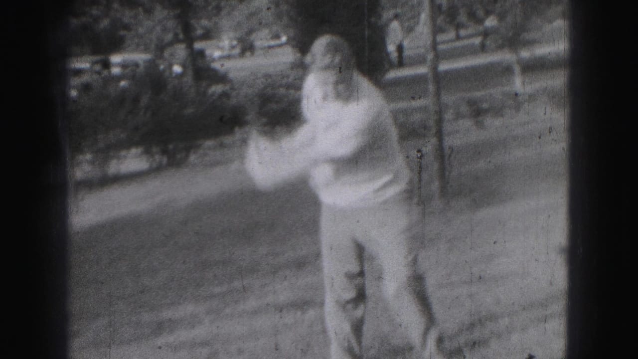 Adult man practices a golf swing on a grassy Harrisburg yard, captured with motion blur on 8mm film.