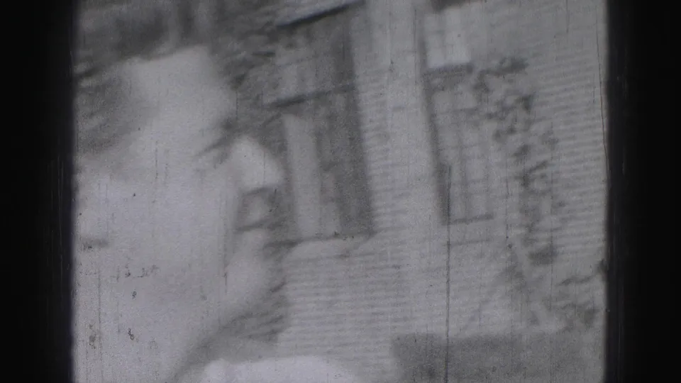 Soft side-view close-up of an adult man near a brick building in metadata-supported 1975 Harrisburg footage.