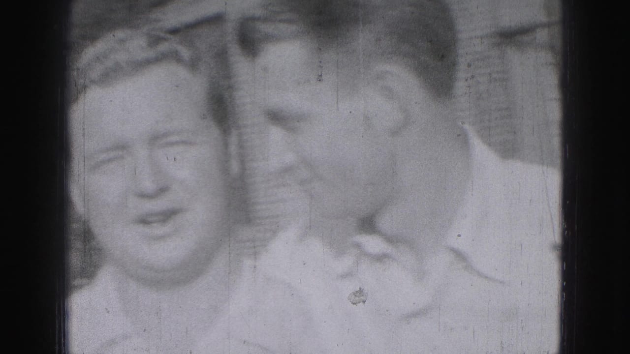 Three young men appear close together in a 1975 Harrisburg outdoor home-movie frame, one leaning in as if speaking quietly.
