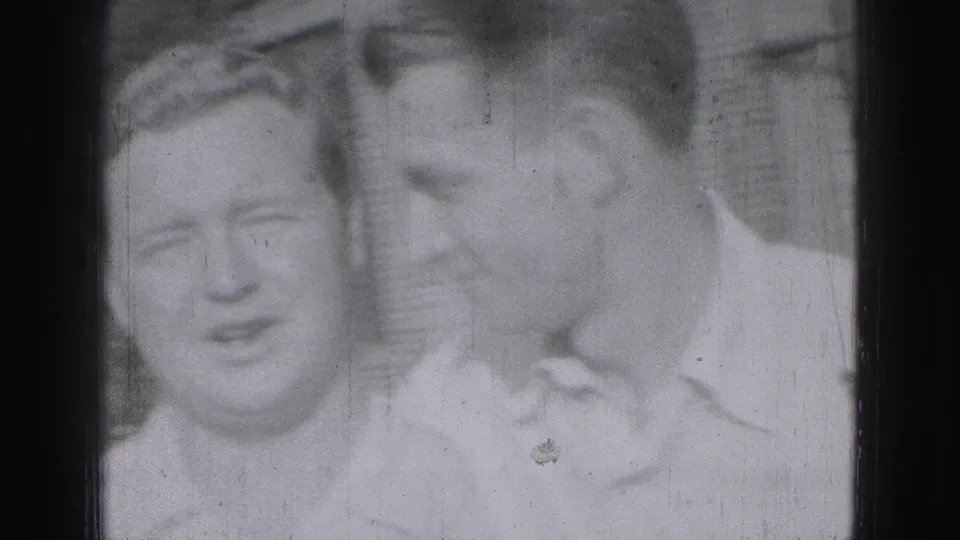 Three young men appear close together in a 1975 Harrisburg outdoor home-movie frame, one leaning in as if speaking quietly.