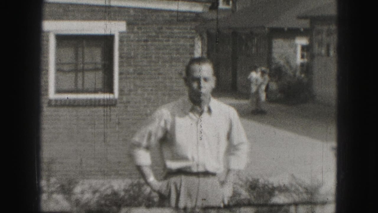Older man stands outside a brick building with hands on hips.