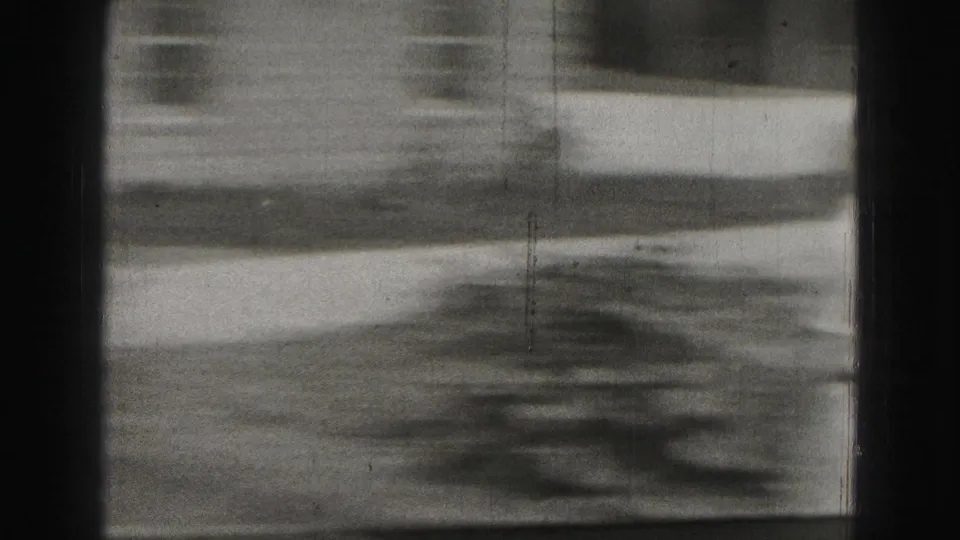 Soft, blurred 1975 8mm frame showing outdoor ground and building detail during camera movement in Harrisburg.