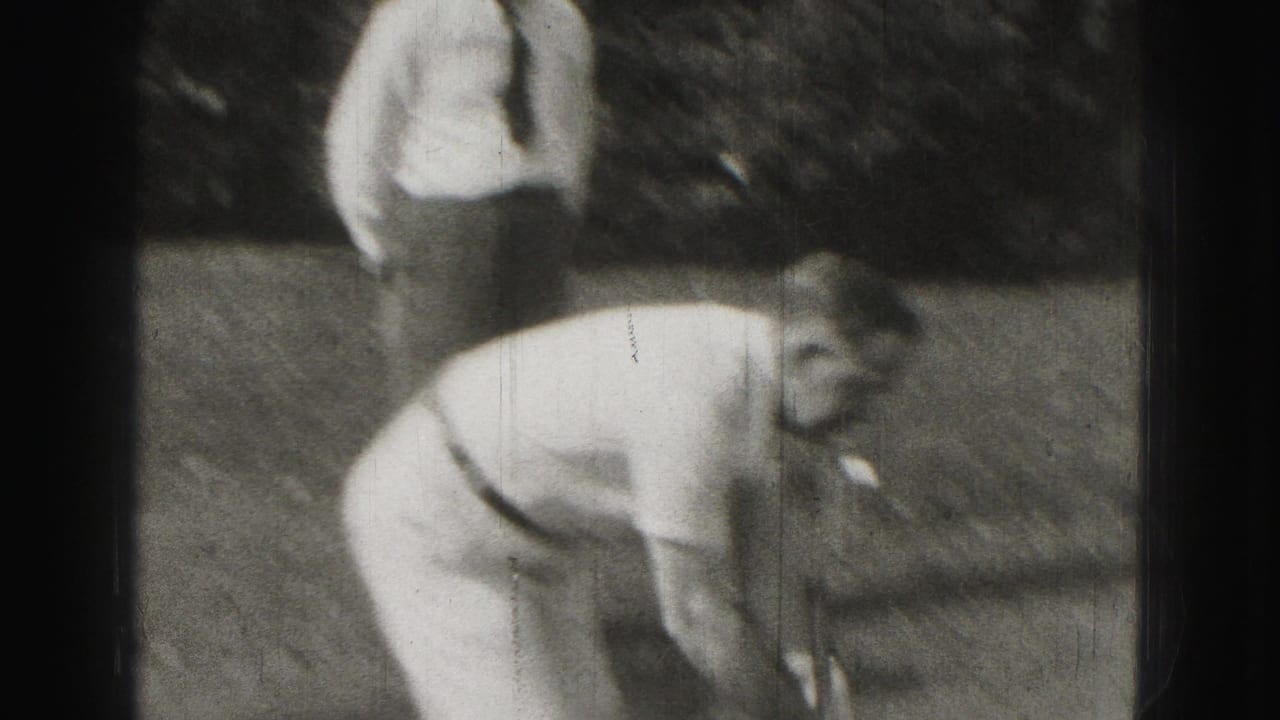 Man bends forward with a croquet mallet in a yard while another man stands behind him.