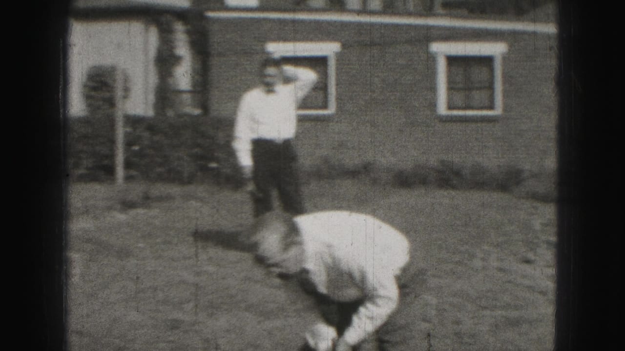 1975 Harrisburg home-movie frame showing men in a suburban backyard, one bending to play croquet while another watches near a house.