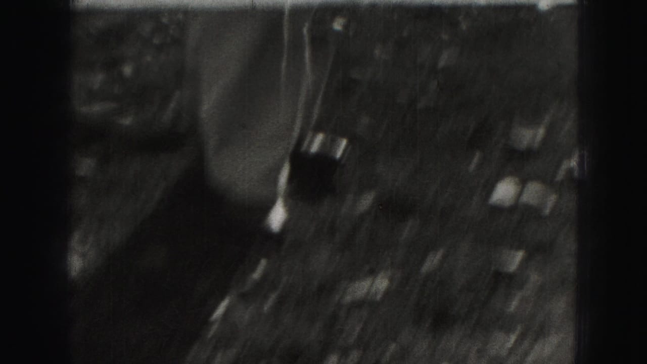 Blurry overhead view of an outdoor yard or street area with dark vertical film borders.