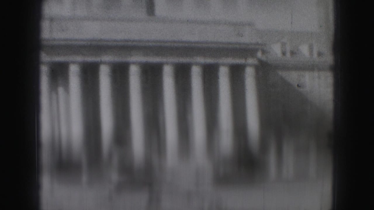 Soft 8mm view of a large white colonnade in Harrisburg, heavily blurred and partly obscured.